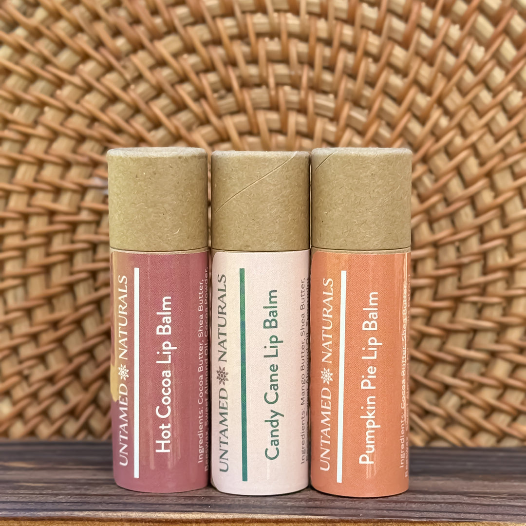 Three lip balms with different flavors on a wooden surface with a woven background